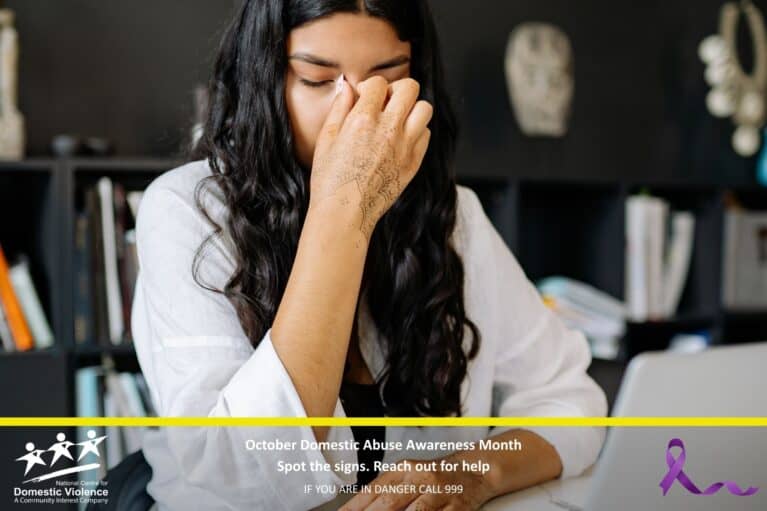 Lady holding bridge of her nose in sadness at a computer desk.