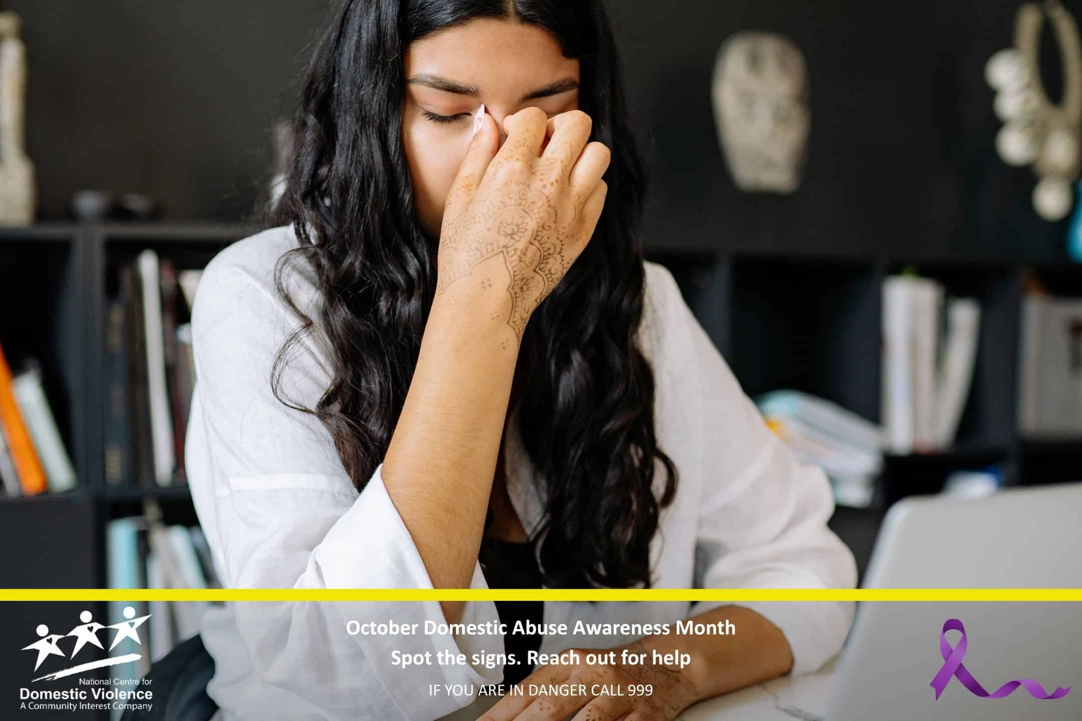 Lady holding bridge of her nose in sadness at a computer desk.