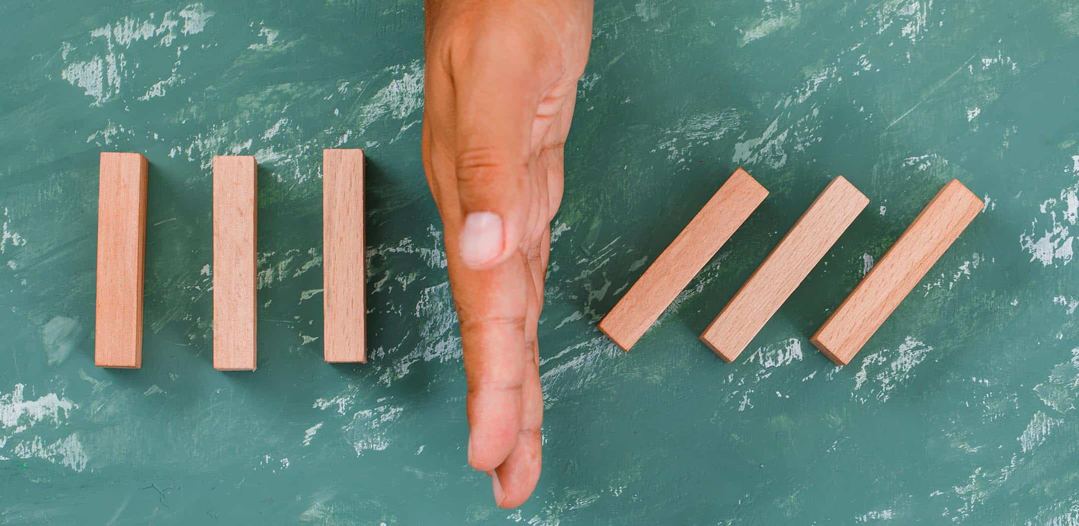 Why is coercive control still misunderstood? 1 Hand barrier dividing wooden blocks signifying control.